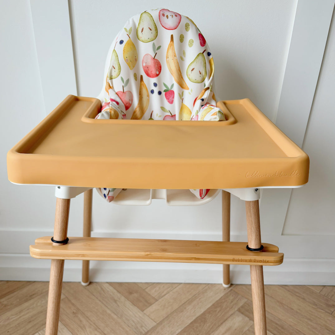 Wooden high chair with a colorful seat cover on a wooden floor.