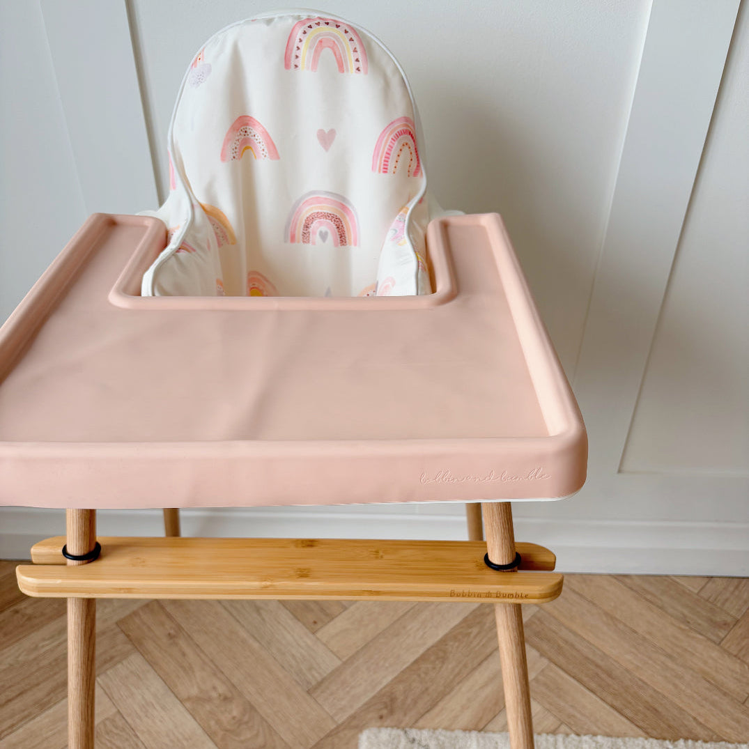 Pink high chair with wooden legs on a wooden floor
