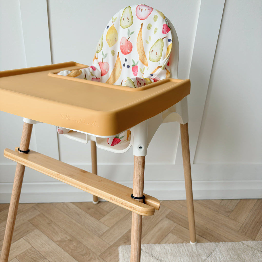 Wooden high chair with a colorful seat cover on a wooden floor.