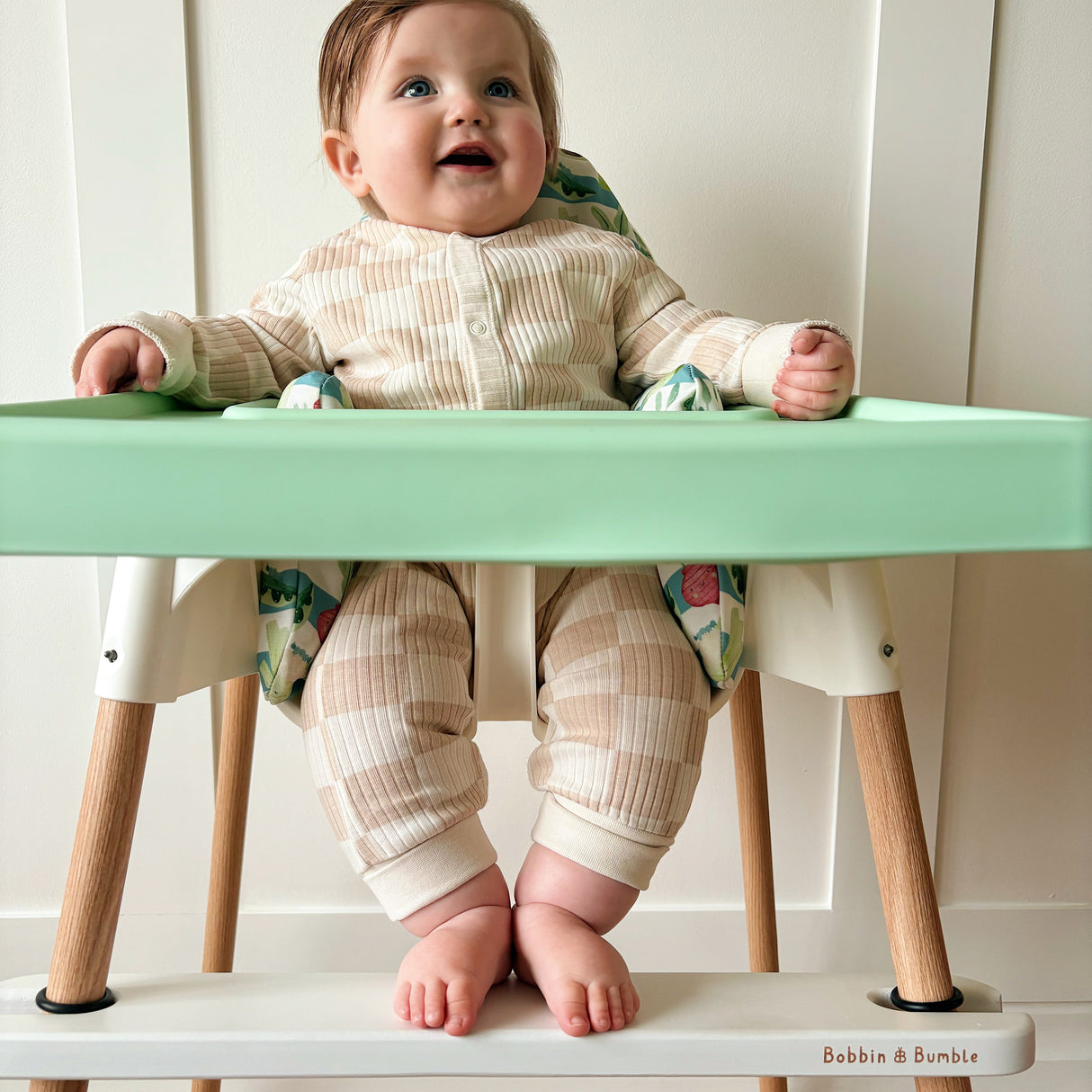 Baby sat in IKEA highchair resting feet on a white Bobbin and Bumble footrest