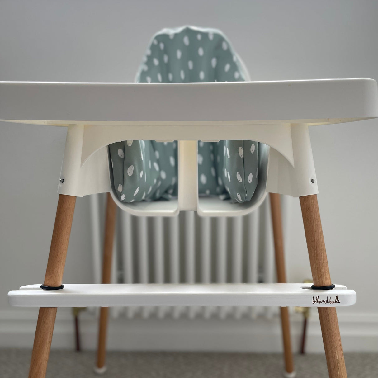 IKEA highchair with wooden legs and a white footrest with Bobbin and Bumble logo