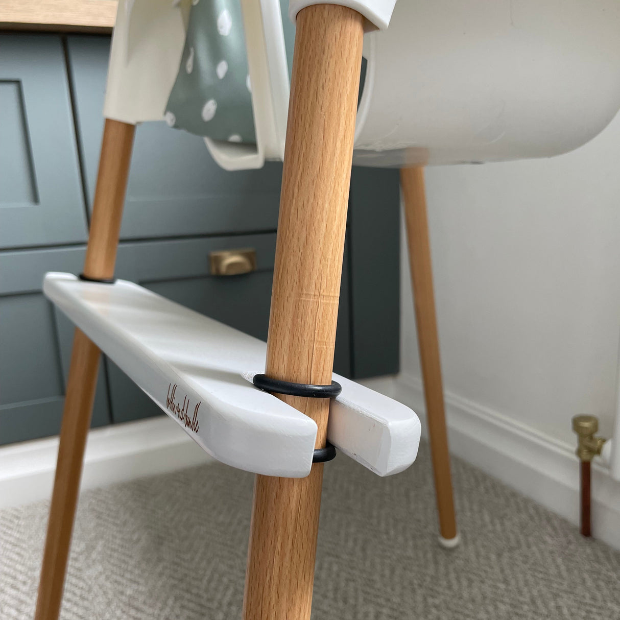 Side view of white footrest on an IKEA highchair leg