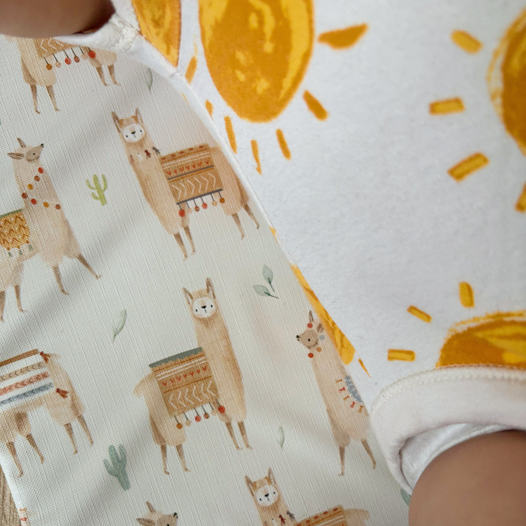 Baby's changing mat with llama pattern and sun pattern on a romper