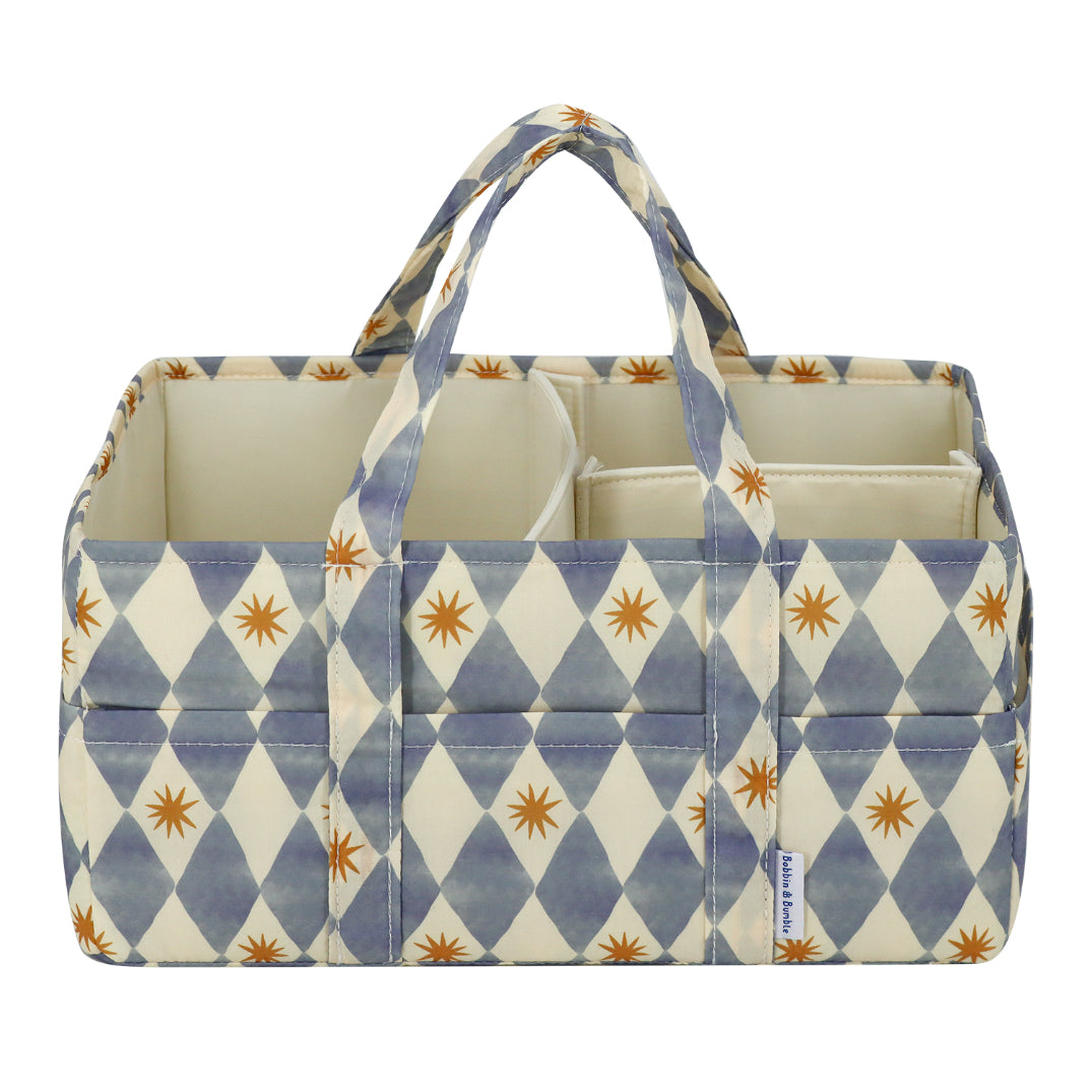 A fabric storage organizer bag with a blue and cream harlequin diamond pattern and small orange starburst accents, featuring two top handles and an open top design.