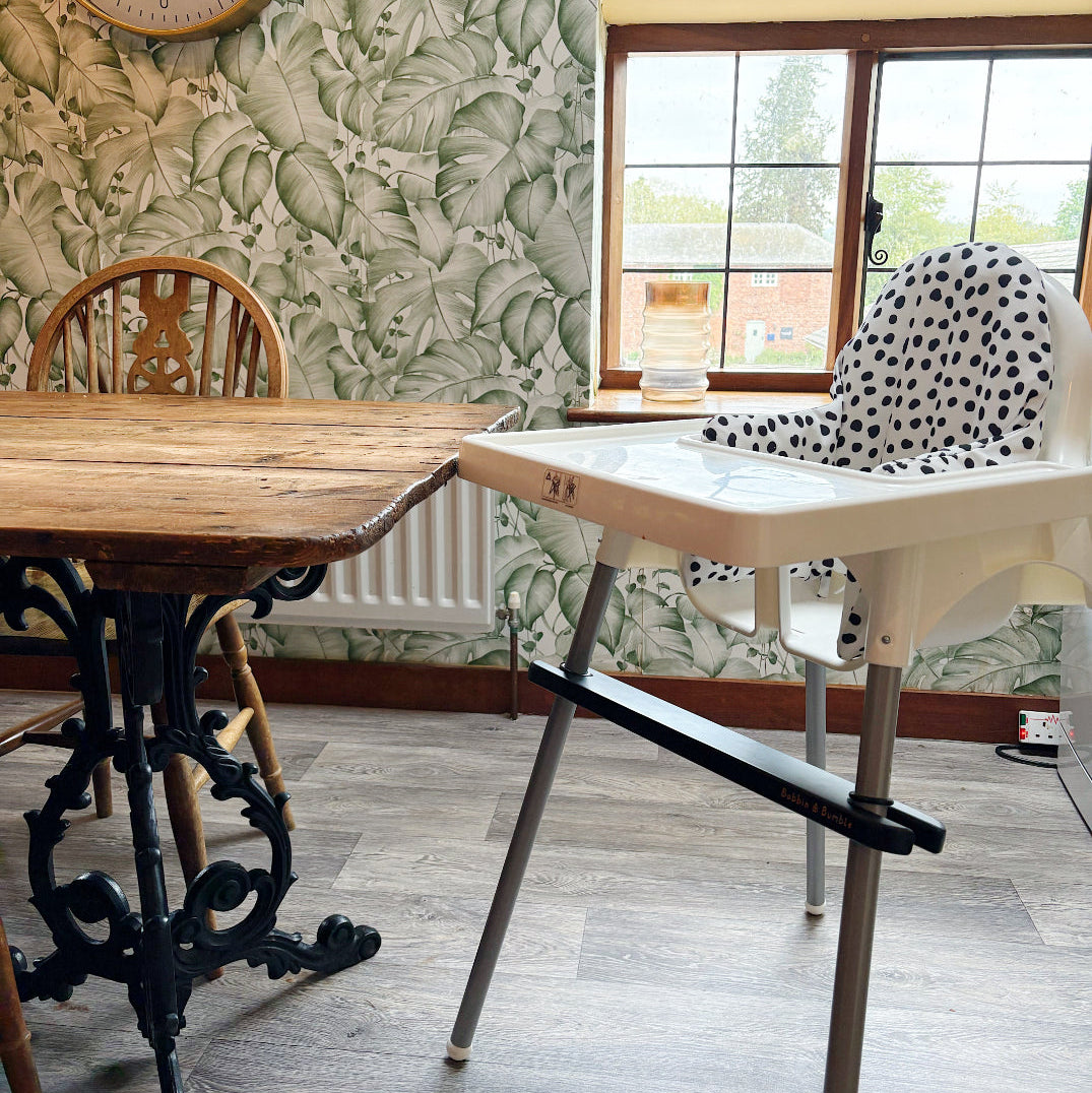 Room with wooden table, high chair, and floral wallpaper