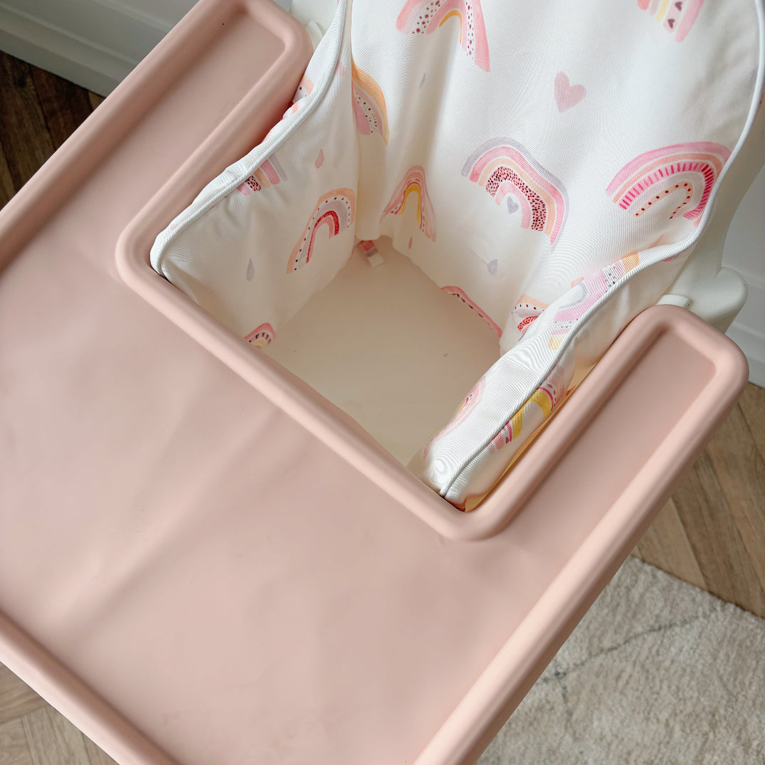 Close up of pink silicone tray cover and rainbow print highchair cushion cover