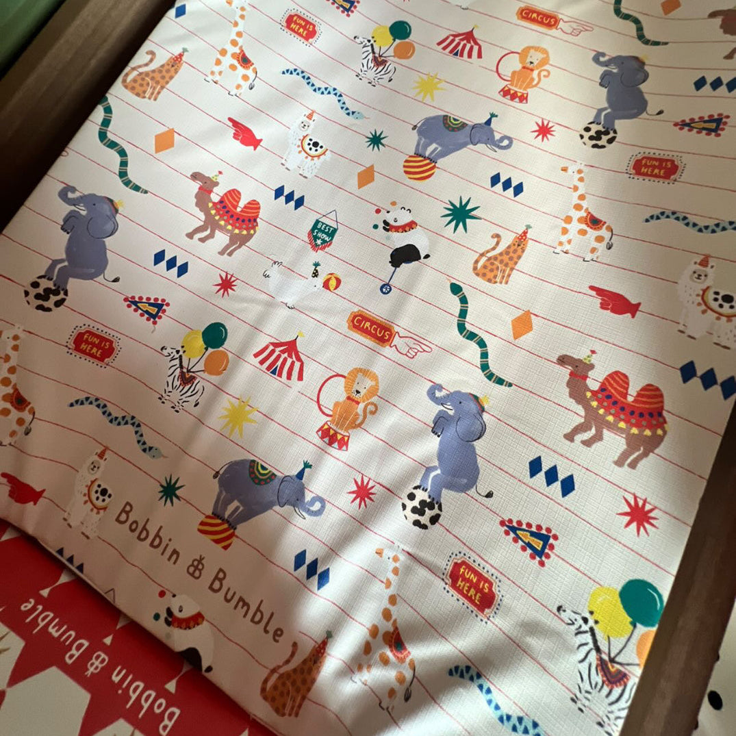 Children's changing mat with animal illustrations on a wooden surface