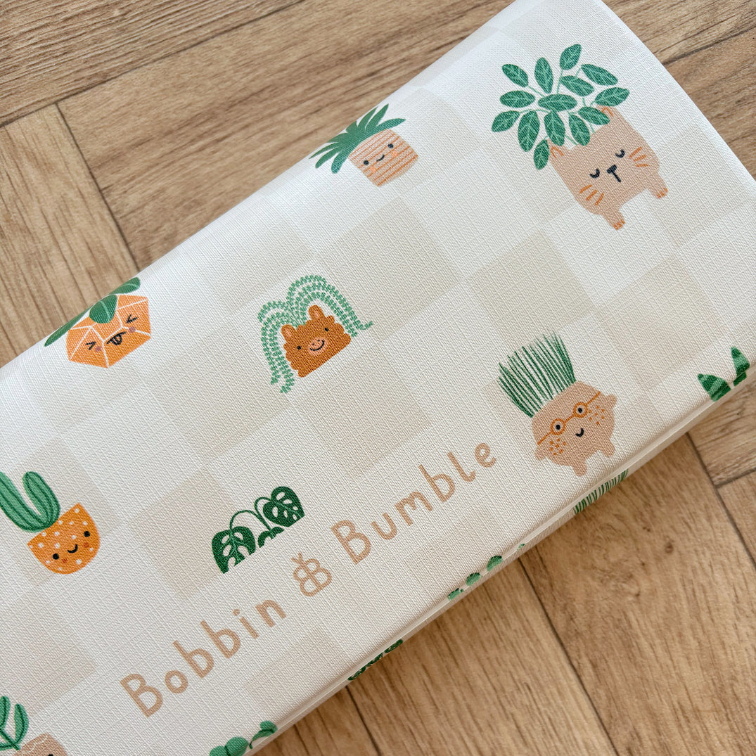 Travel changing mat with cartoon plant designs and 'Bobbin & Bumble' text on a wooden surface