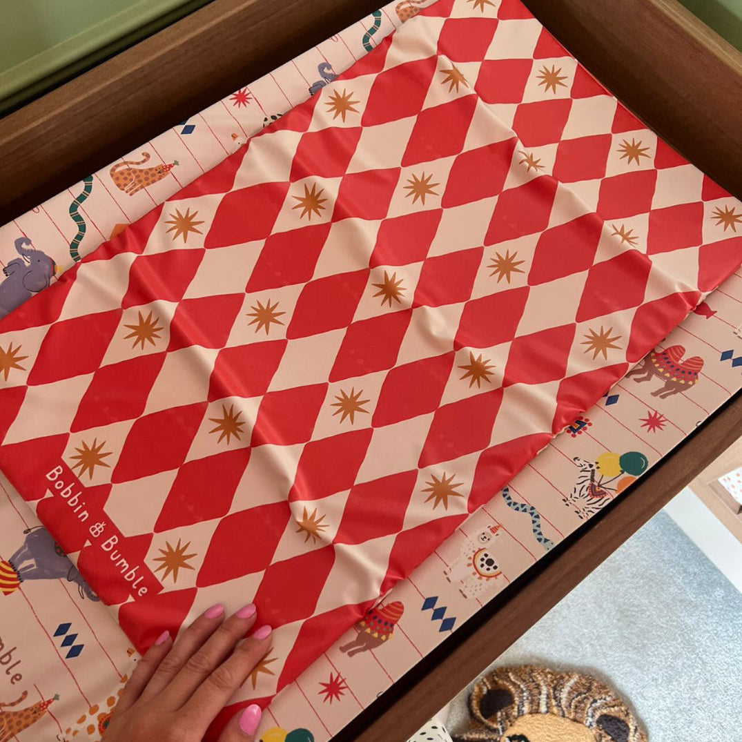 Red and white checkered travel changing mat on a wooden surface changing table