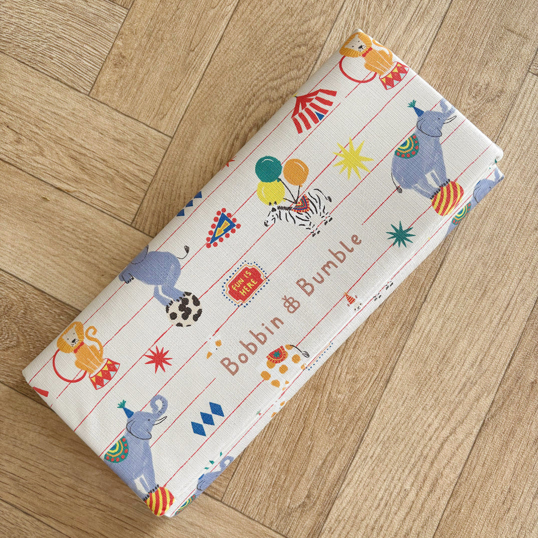 Travel changing mat with circus animal designs on a wooden floor