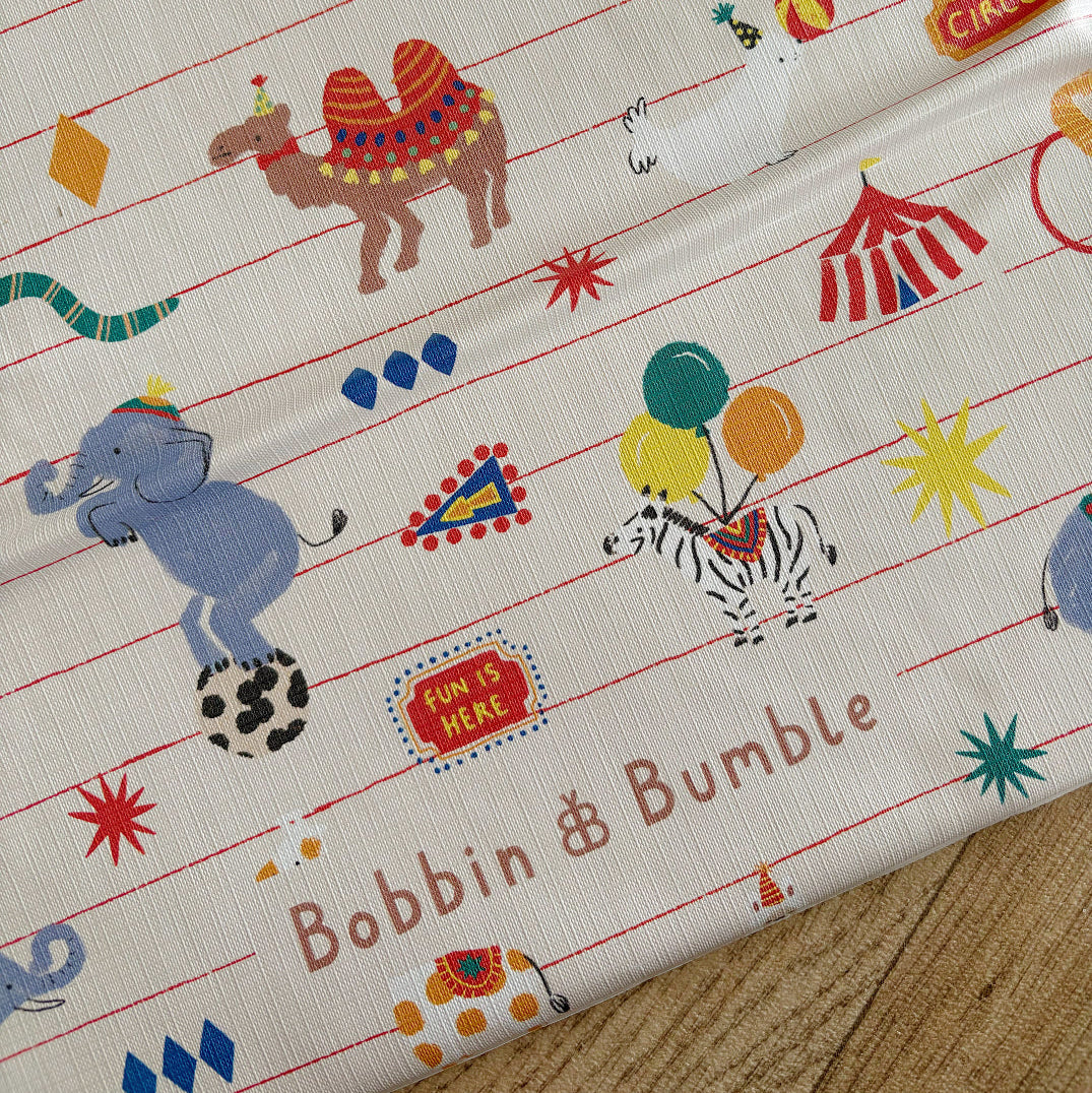 changing mat with circus-themed design featuring animals and objects, branded 'Bobbin & Bumble'.