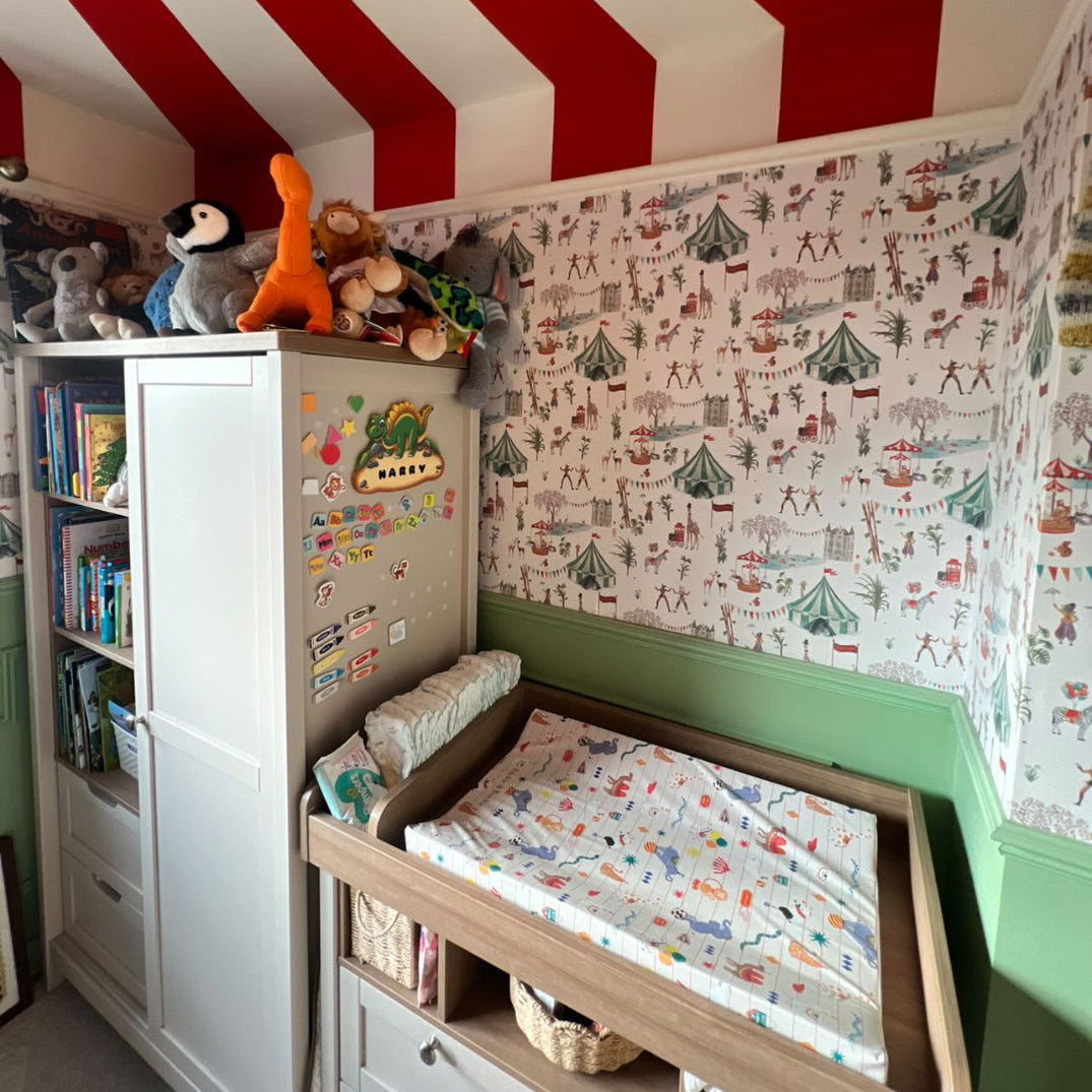 Children's room with red and white striped ceiling, bookshelf, and crib with changing table.