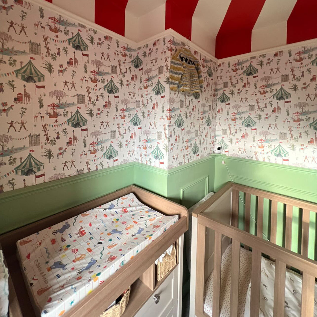 Children's room with red and white striped ceiling, patterned wallpaper, and wooden cribs.