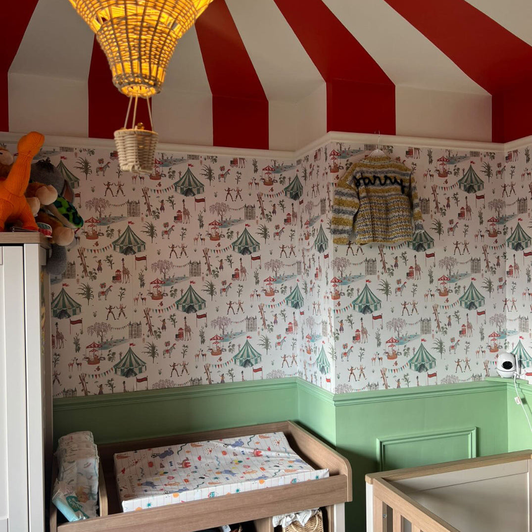 Nursery room with striped red and white ceiling, patterned wallpaper, and wooden furniture.