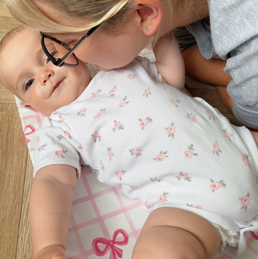 mum kissing a baby on a checkered changing mat