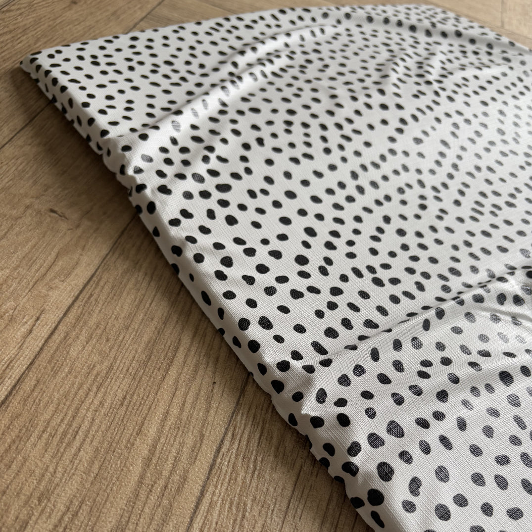 Polka dot travel changing mat laid out on a wooden surface