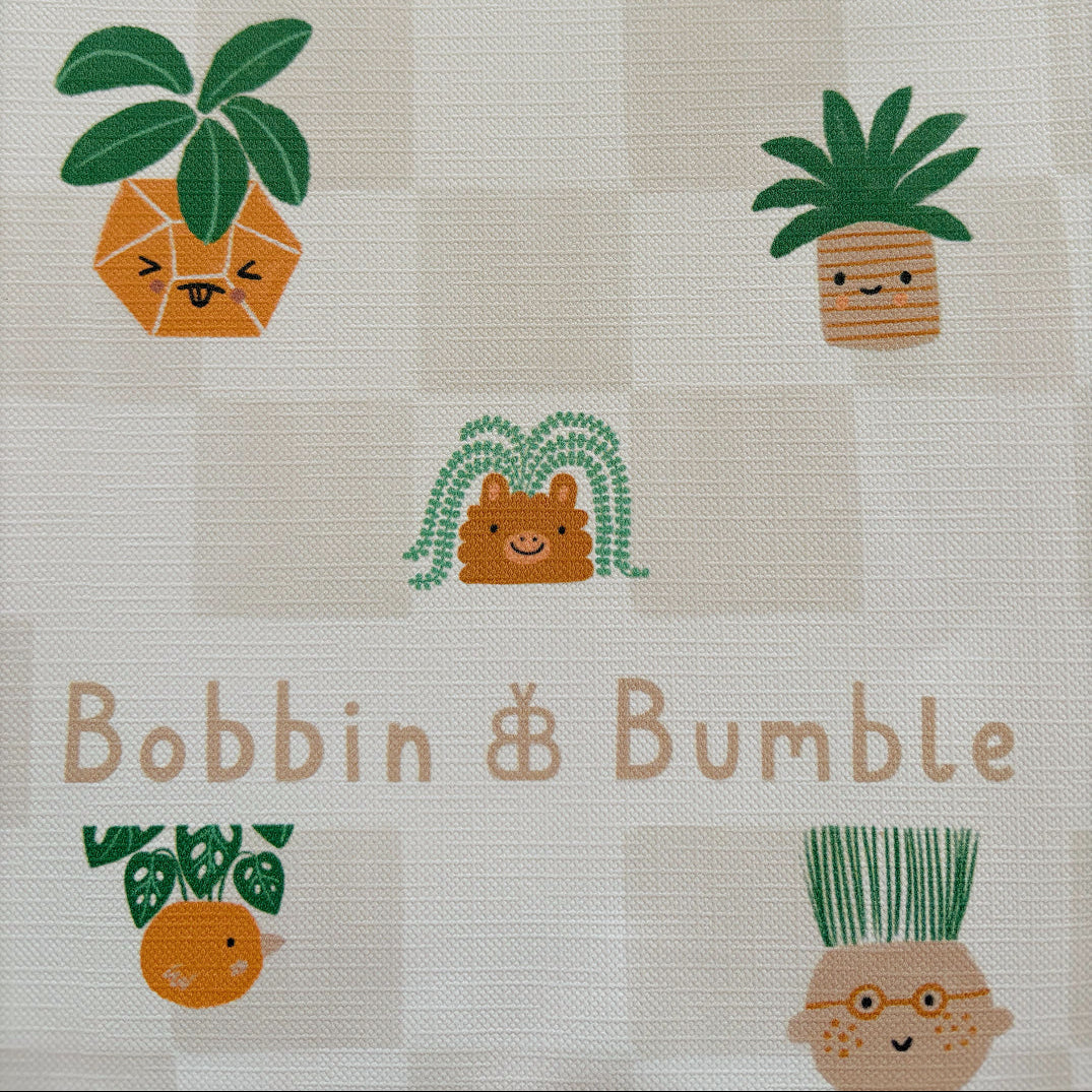 Fabric with cartoon plants and 'Bobbin & Bumble' branding on a checkered background