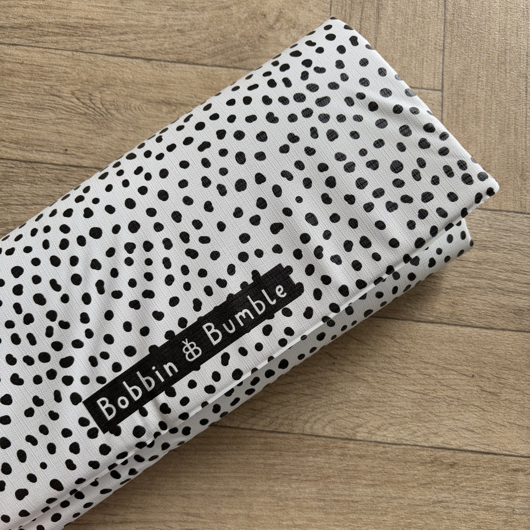 Changing mat with black and white polka dot fabric with 'Bobbin & Bumble' label on a wooden surface