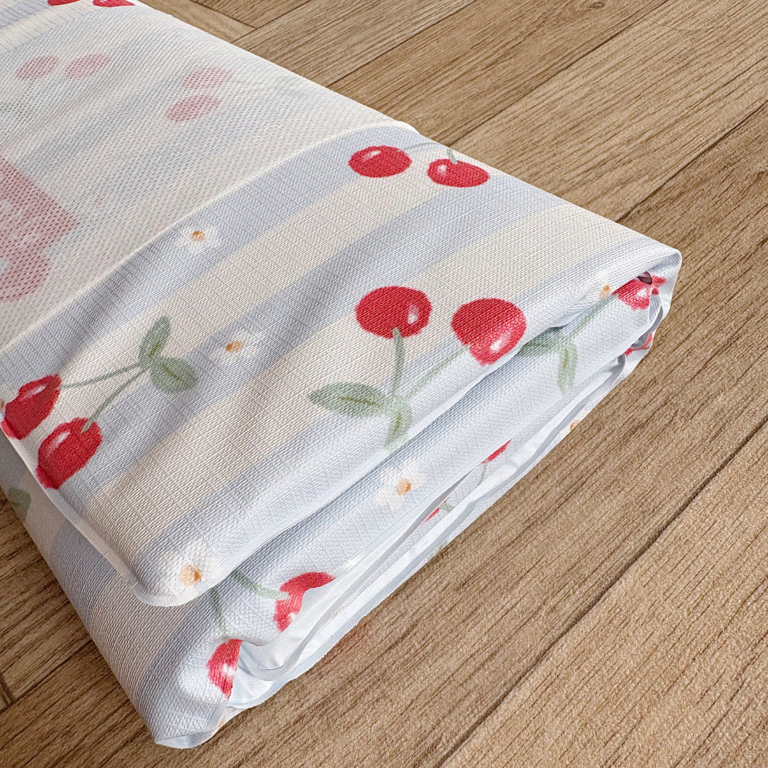 Folded changing mat with cherry pattern on a wooden surface