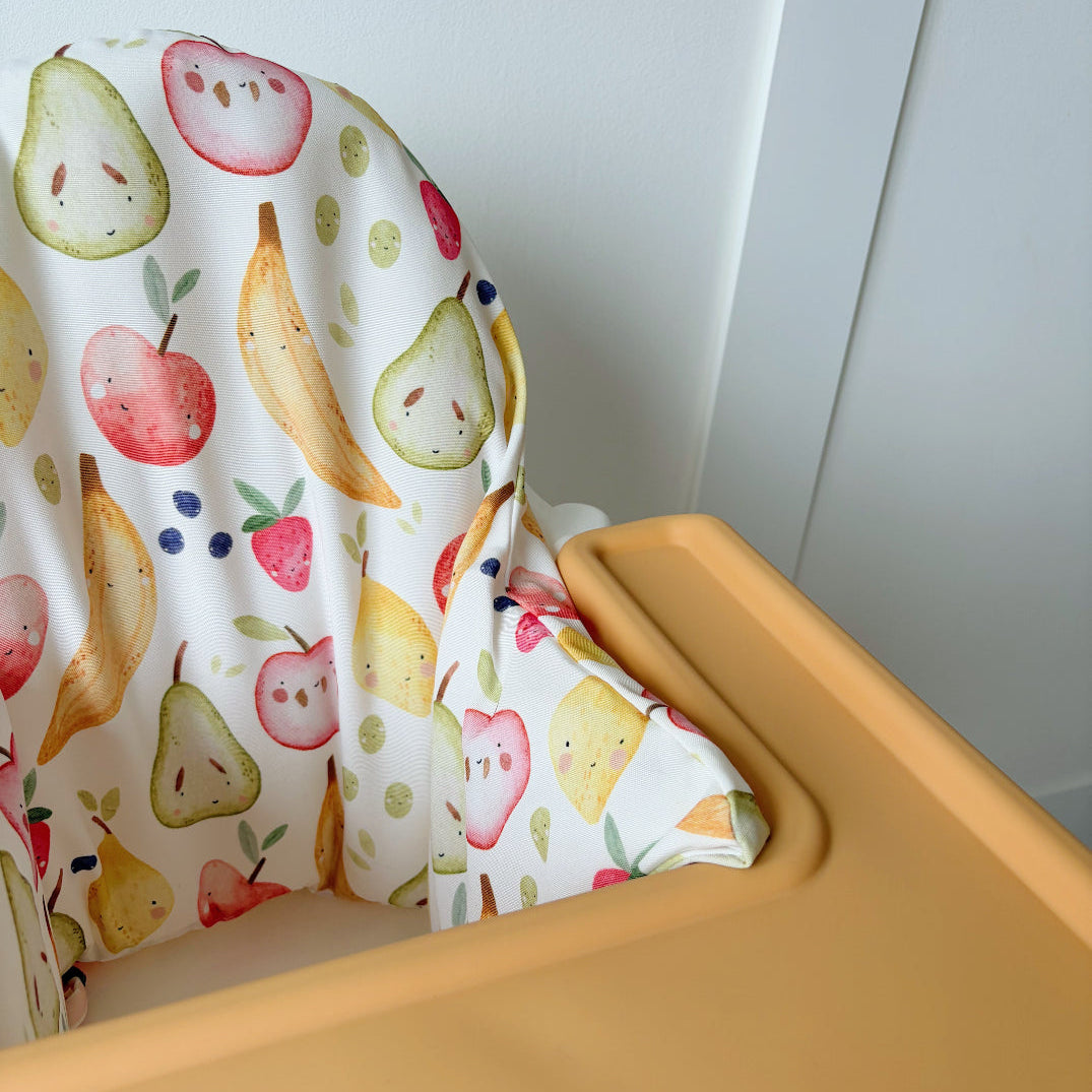 Yellow chair with a colorful fruit-patterned cushion against a white wall.