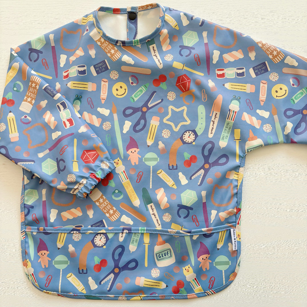 Colorful children's apron with various items on a white background