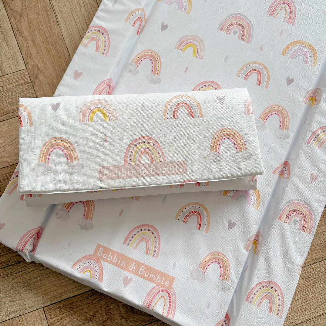 Baby changing mat with rainbow pattern and Bobbin & Bumble branding on a wooden floor.