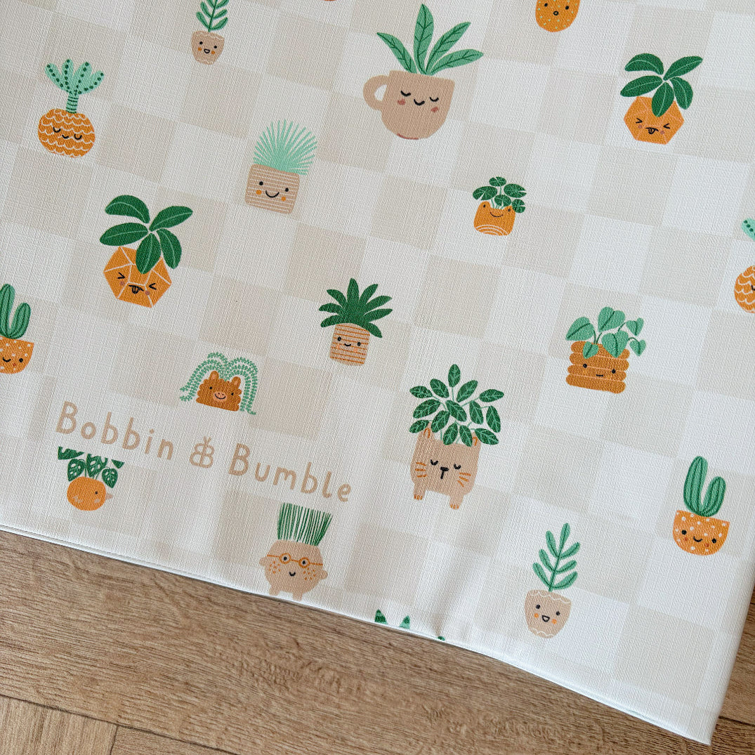 Baby Changing Mat with cartoon plant designs and 'Bobbin & Bumble' branding on a wooden surface.