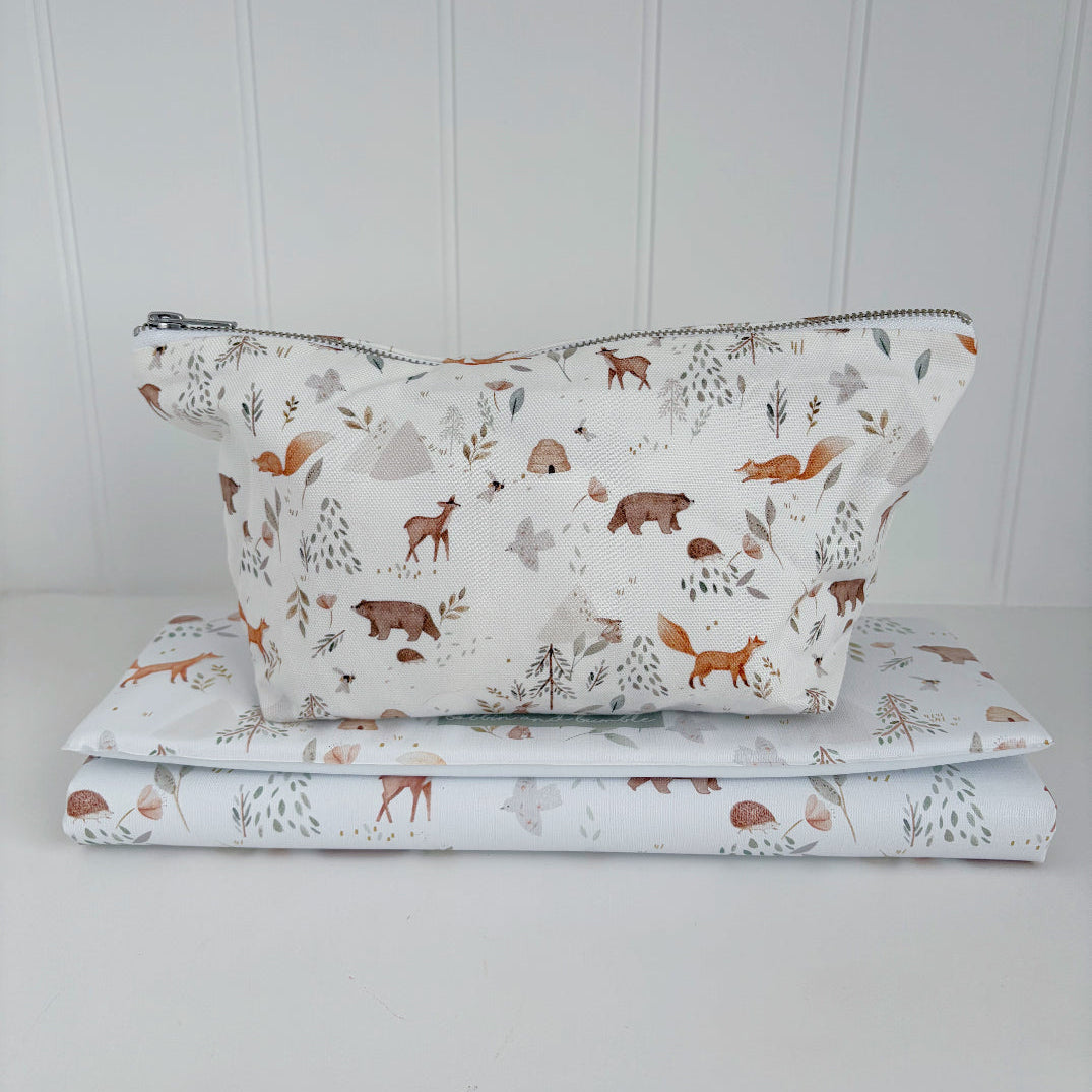 Folded travel baby changing mat with a matching nappy pouch on top. Both with animal pattern on a white background