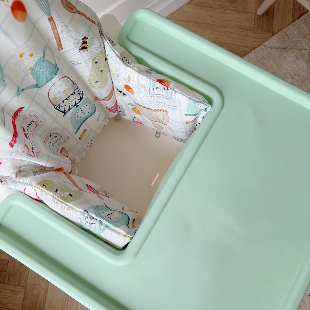 baby highchair with mint green tray cover with patterned cushion on a wooden floor