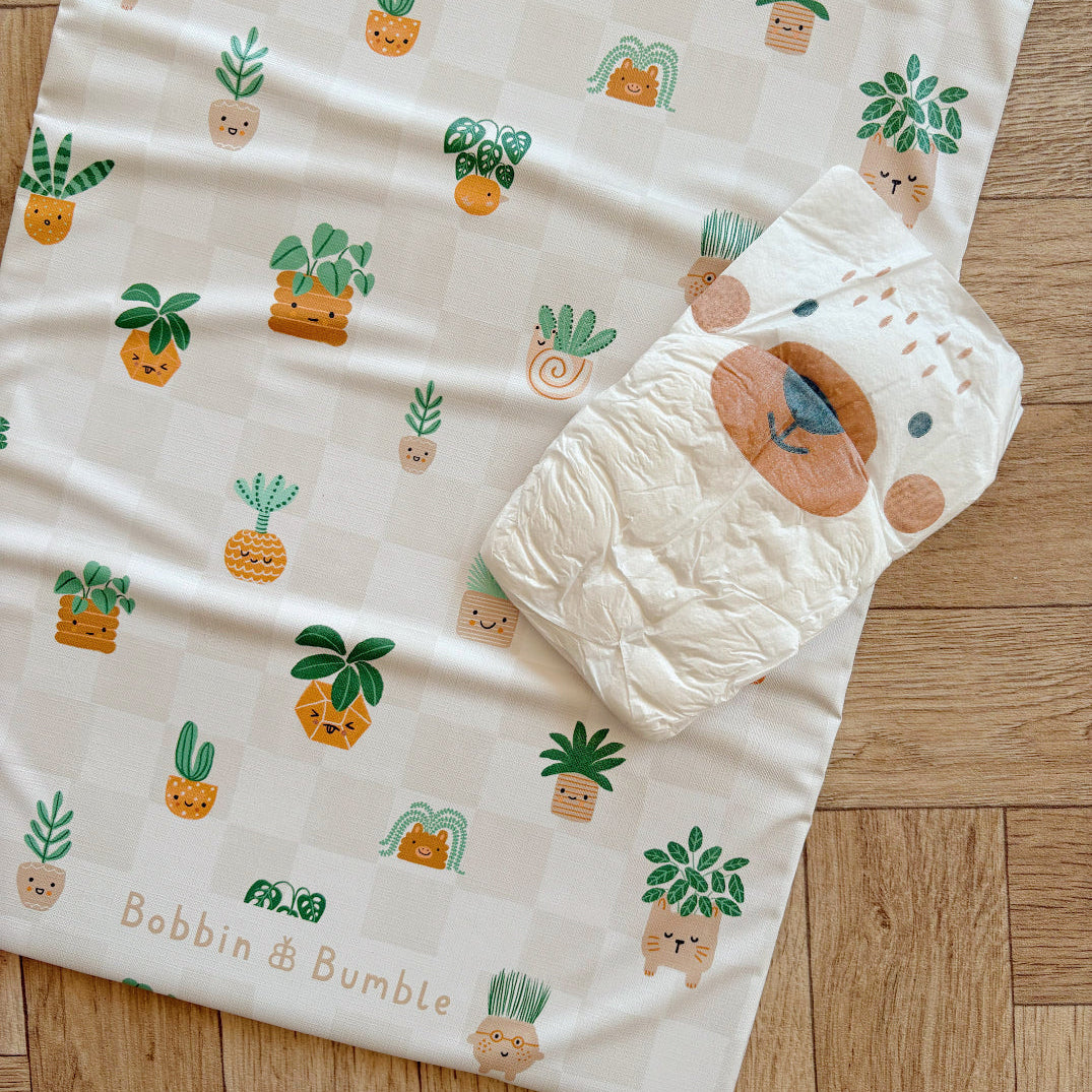 Baby changing mat with cartoon plant pattern on a wooden surface