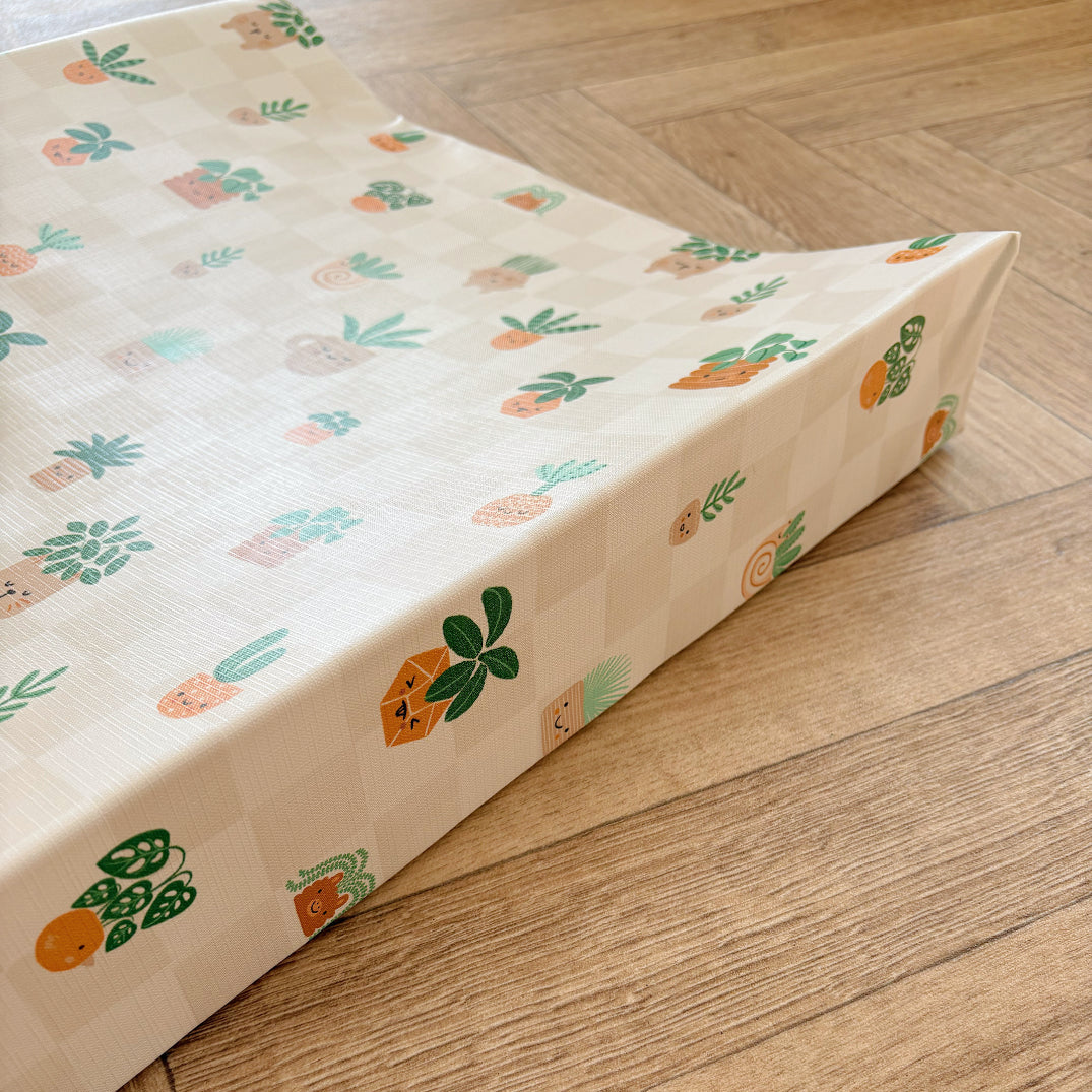 Baby wedge changing mat with house plant pattern on a wooden floor