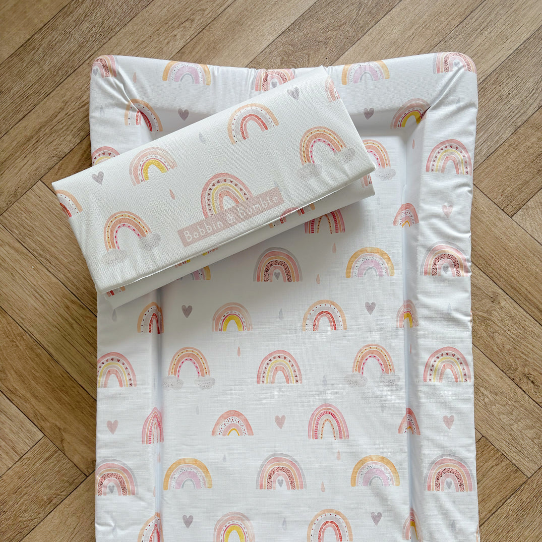 Baby changing mat set with rainbow pattern on a wooden floor
