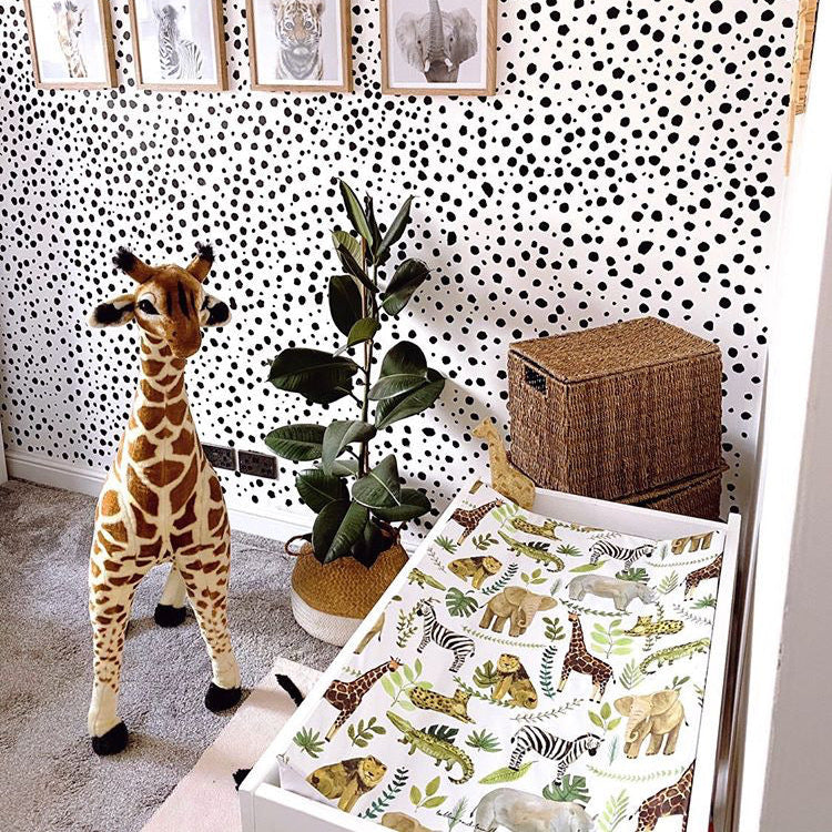 Spotty black and white walls in a nursery with a giraffe teddy and a safari print changing mat