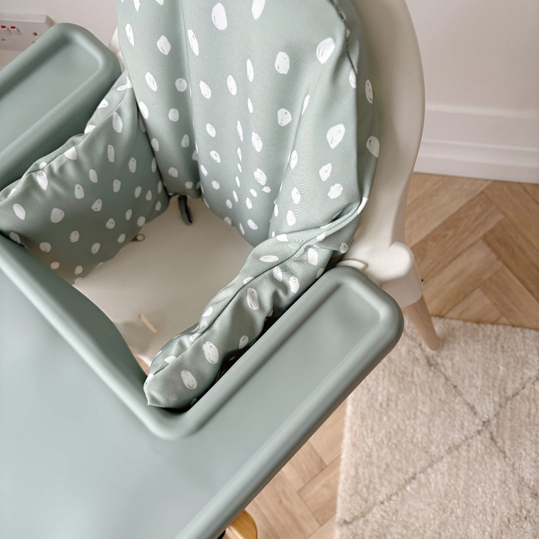 High chair with a polka dot cushion on a wooden floor.