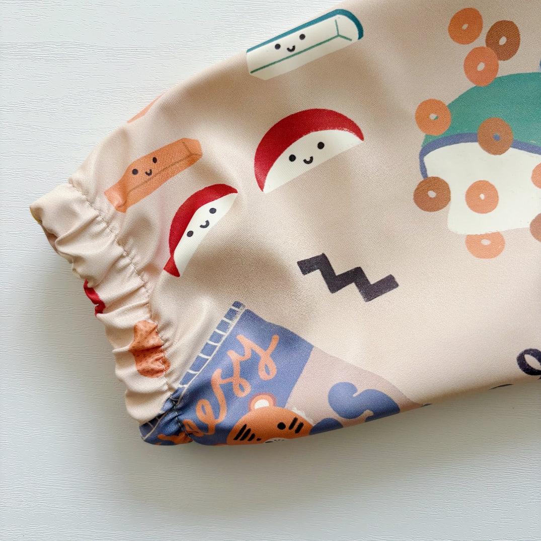 Close-up of an elasticated sleeve from a baby bib with a cartoon food design on a light background