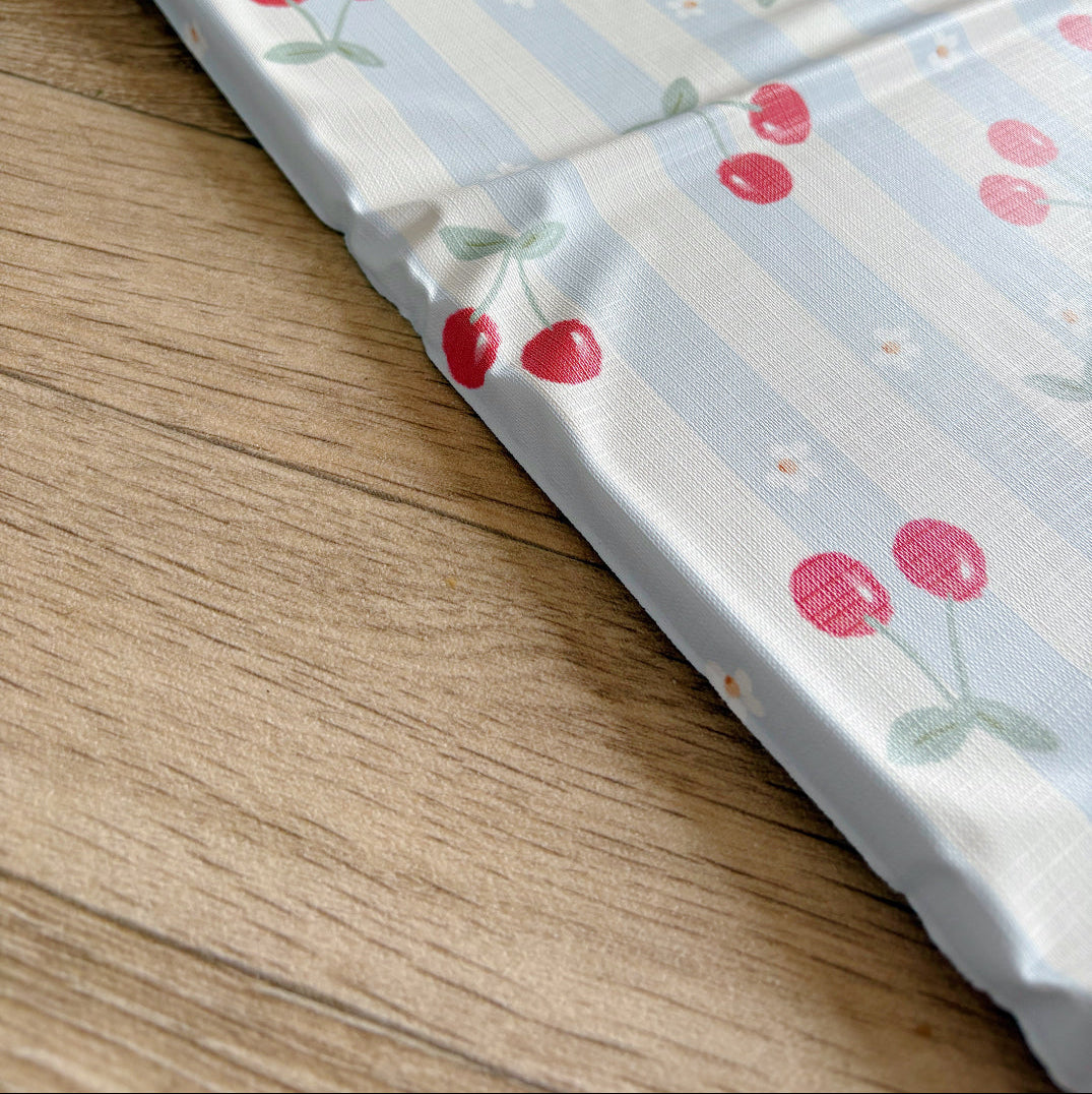 Foldable travel changing mat with cherry pattern on a wooden surface