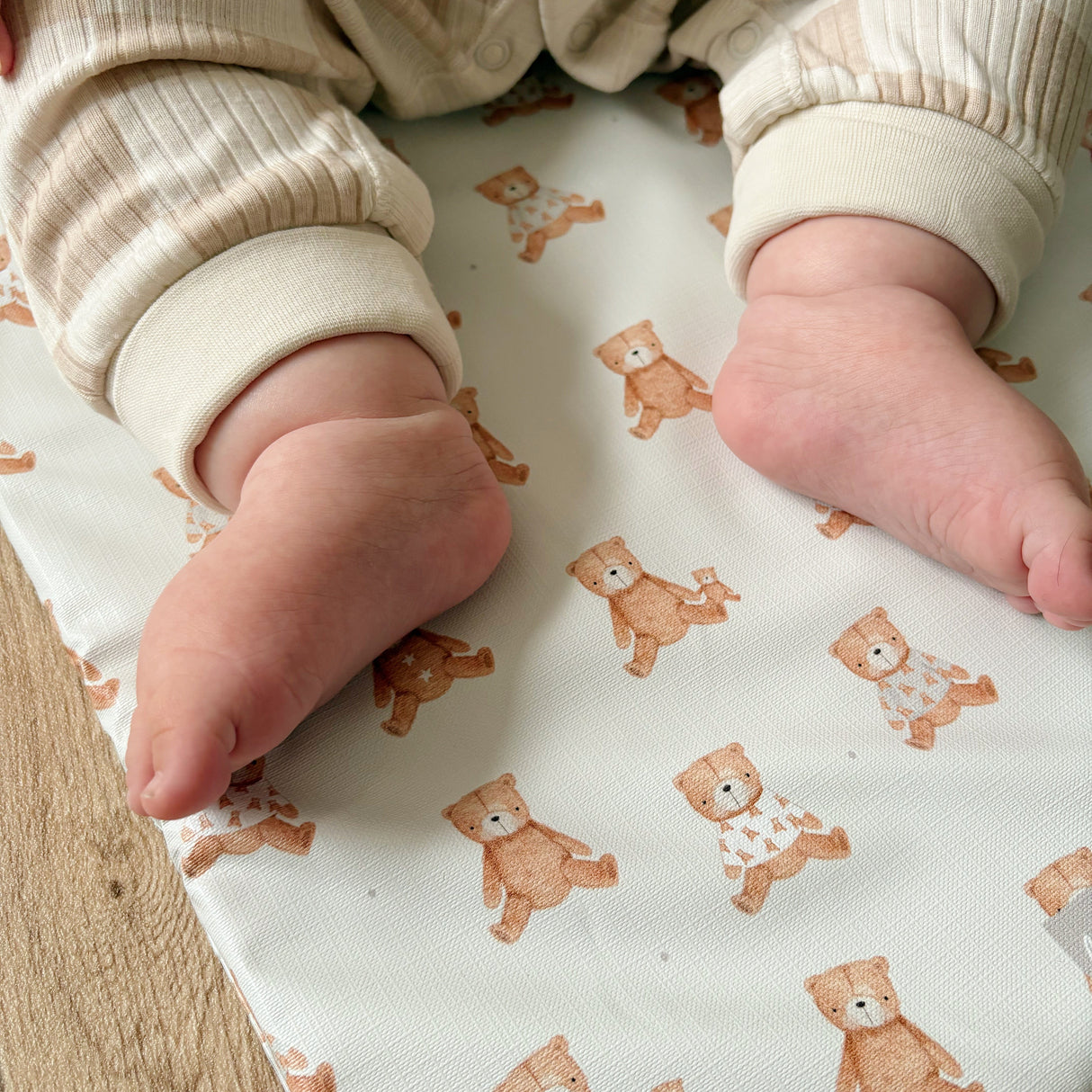 Close up of baby feet on top of a teddy bear changing mat