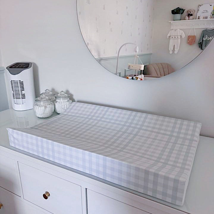 White dresser with a checkered changing pad in a nursery setting