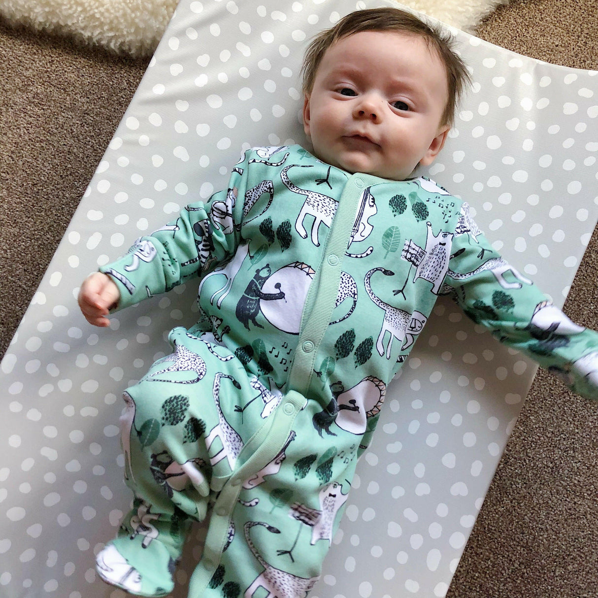 Anti-Roll Wedge Changing Mat - Grey Spots with baby laying on top.