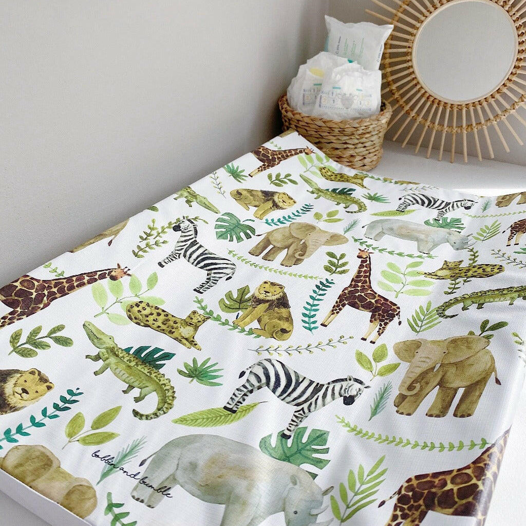 Anti-Roll Wedge Changing Mat - Safari Animals Print with a sunburst mirror and a nappy caddy on a grey background