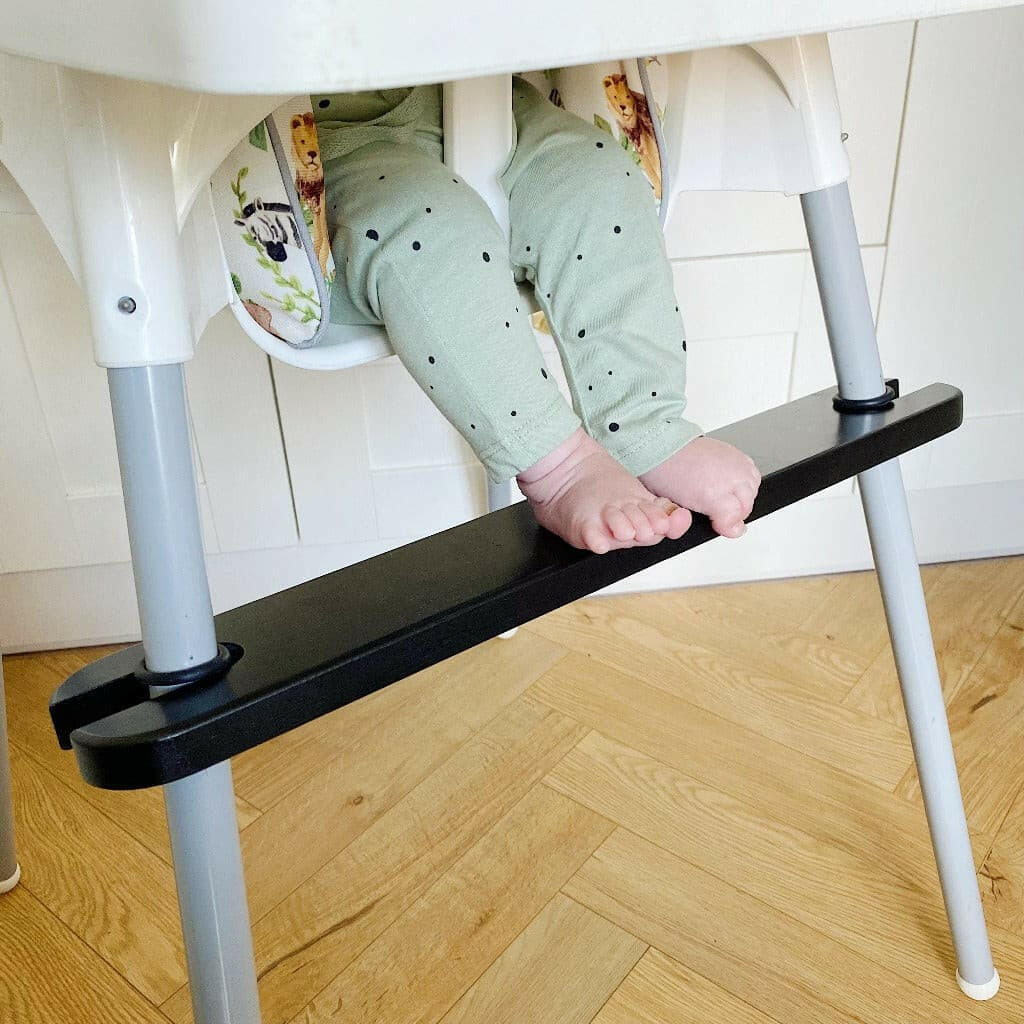 Baby feet resting on a black IKEA highchair footrest
