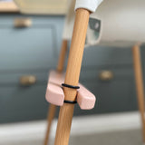 Side view of pink IKEA highchair footrest fitted on the leg of the highchair. Shows two o-rings either side