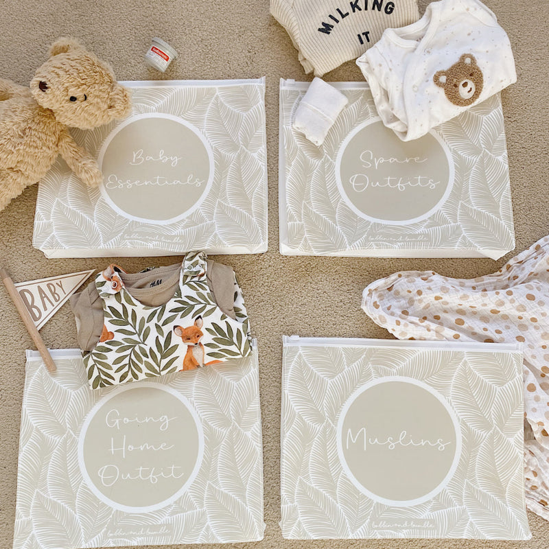 Baby clothing and accessories on clear bags with labels on a beige surface