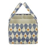 A fabric storage basket with a blue and cream harlequin diamond pattern and small orange starburst accents, featuring two top handles and a cream-colored interior.