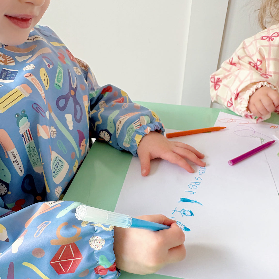 Two children coloring at a table with crayons and paper.