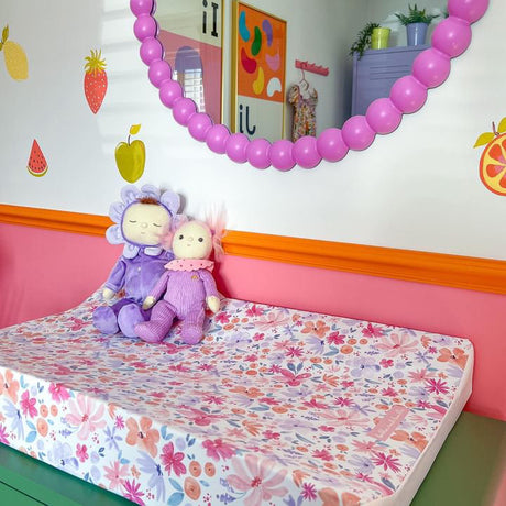 Pink floral wedge changing mat on green dresser with pink bobbin mirror on white wall