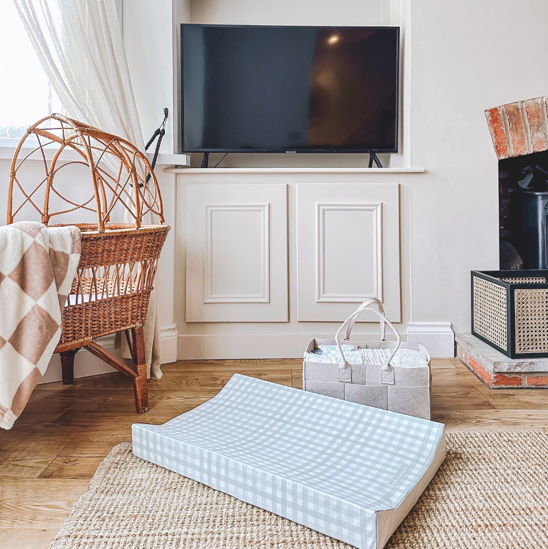 Room with a crib, television, and baby items on a wooden floor.