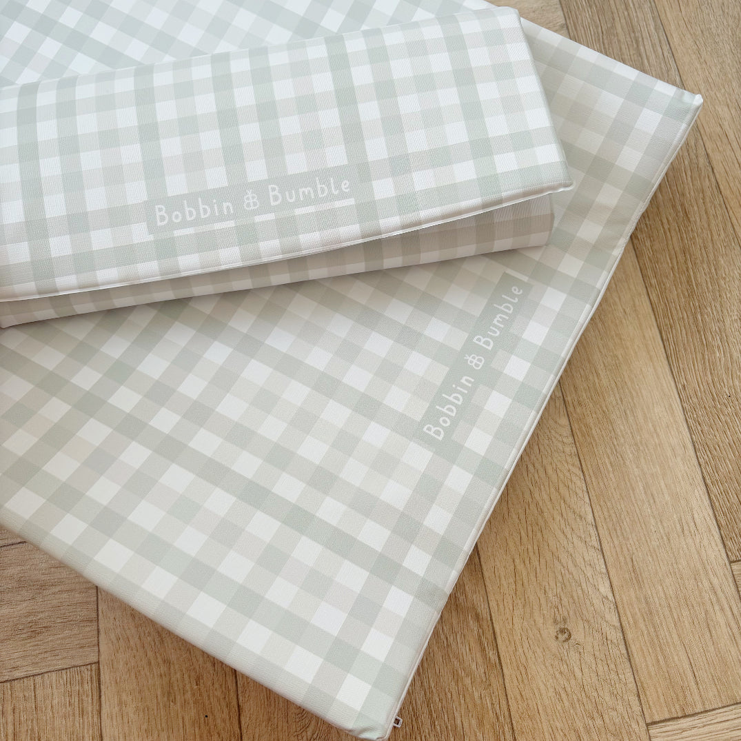 Two  Bobbin & Bumble changing mats in a pale green gingham on a wooden floor