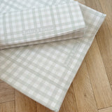 Two  Bobbin & Bumble changing mats in a pale green gingham on a wooden floor