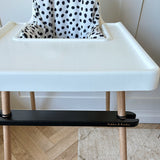 White high chair with wooden legs on a wooden floor